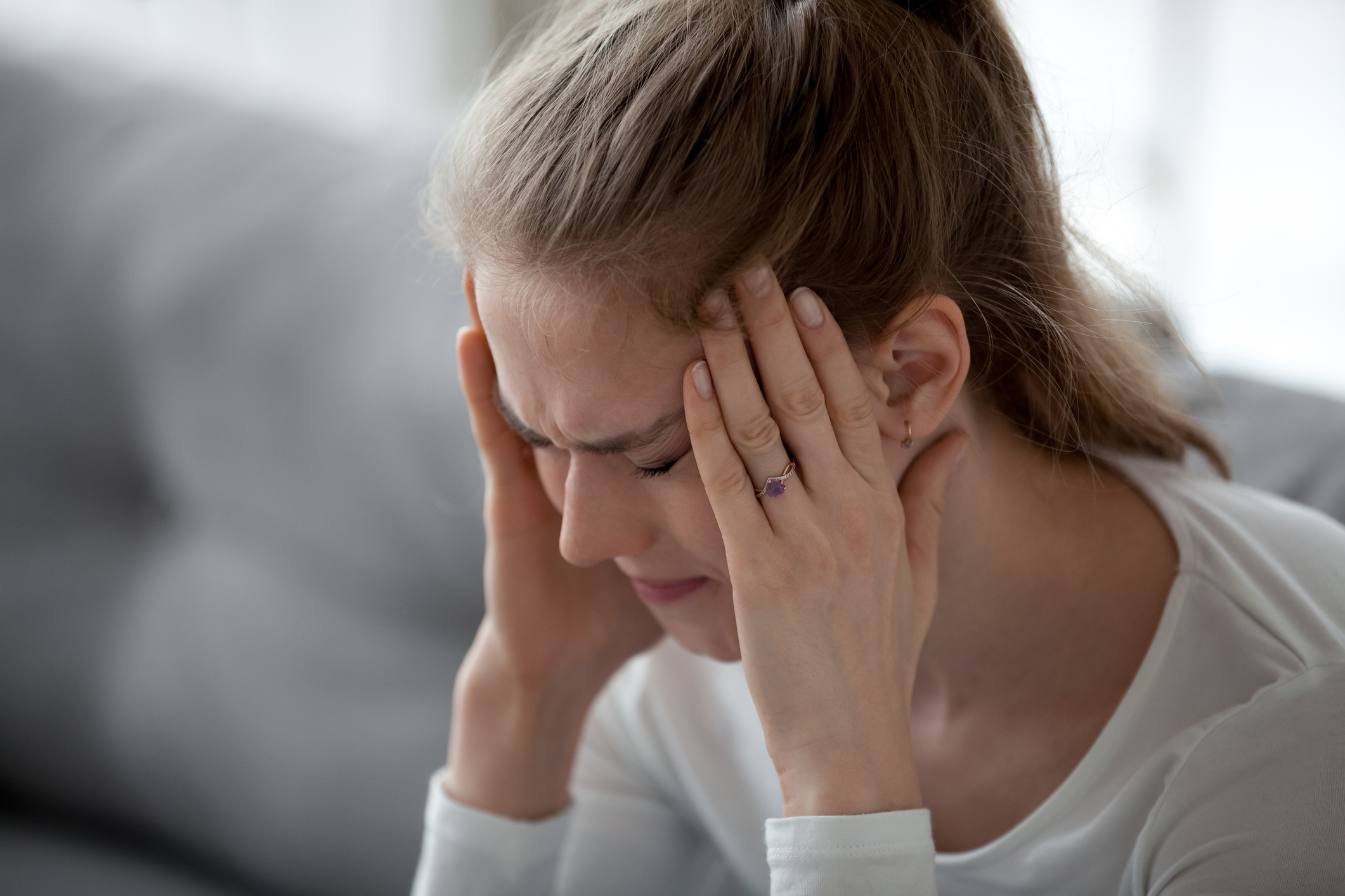 Stressed young sick woman having strong terrible headache massaging temples